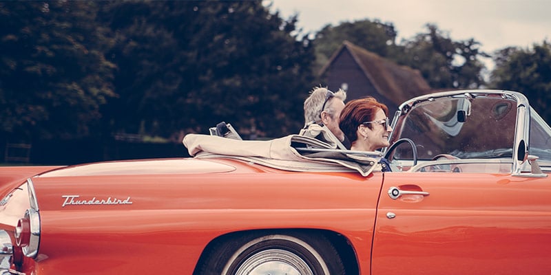 retired couple cruising in their convertible