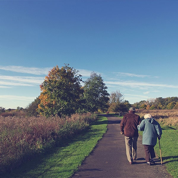 elderly couple walking down a path together