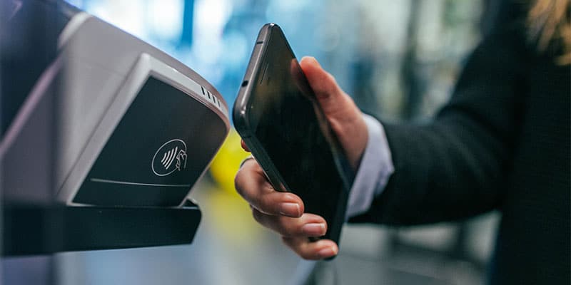 person scanning their phone next to a tap-to-pay terminal