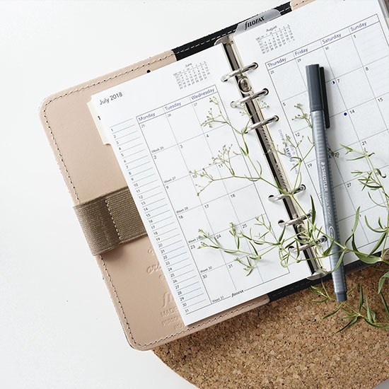 calendar planner open with a pen and floral sprig on top