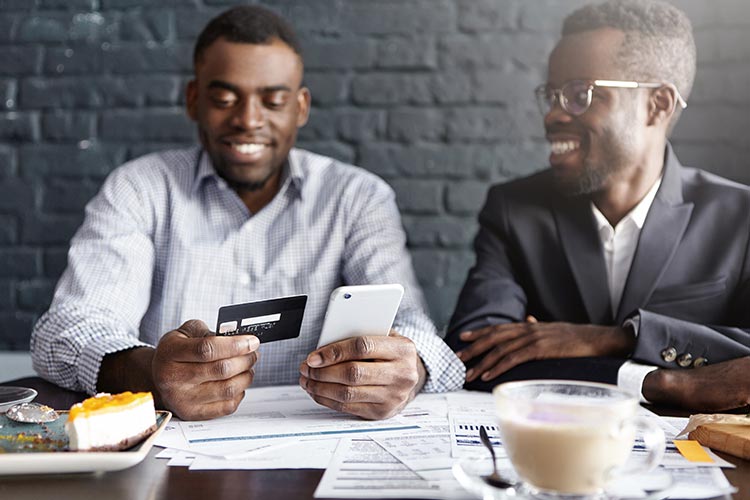 business partners at lunch together, one has a credit card and smartphone in his hands