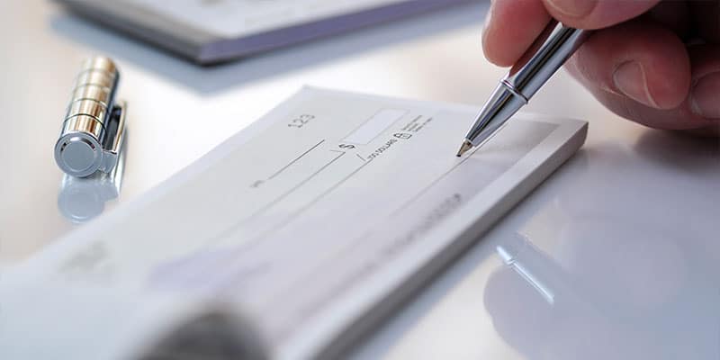 close up of hand signing a checkbook