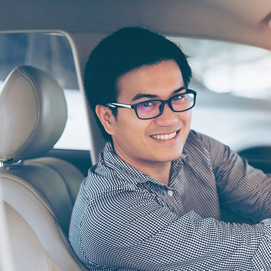 smiling man sitting in the driver seat of his car