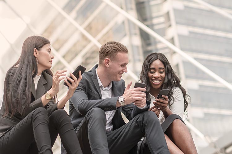 group of business professionals checking their phones and smiling together