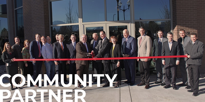Deseret First staff along with members of the West Valley Community, DFCU's Board of Directors, and many others at the Ribbon cutting of the DFCU Operations Center, with a text overlay: Community Partner