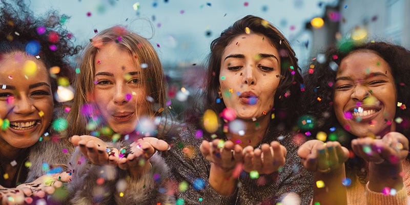 group of young women blowing confetti and laughing