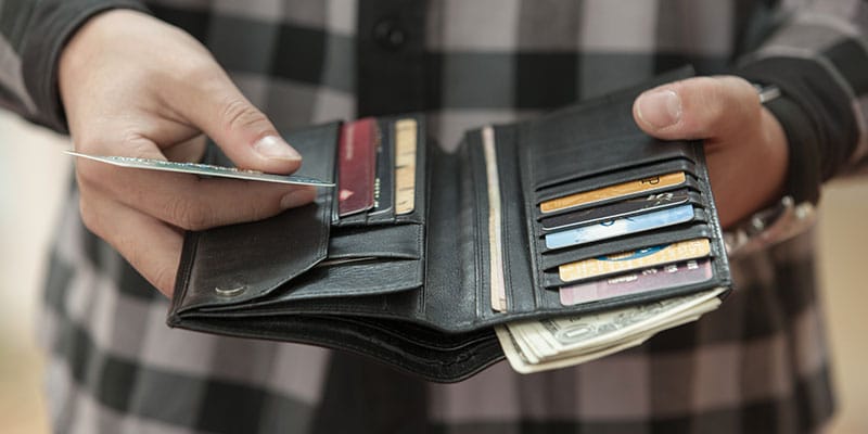 man holding his wallet out, credit card in hand
