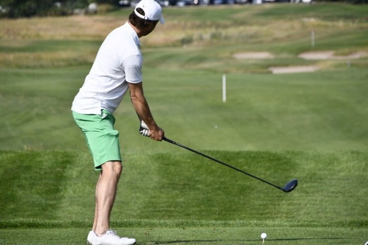 a male golfer preparing to swing the club on the green