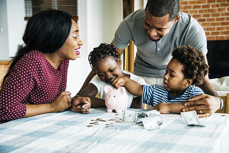 family at the table together, counting their money into a piggy bank
