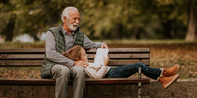 Grandfather on a park bench with child