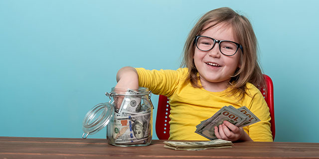 A little girl pulling money from a jar.